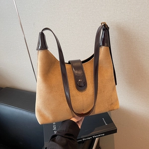 Retro tan suede hobo bag with dark brown leather straps shown against a minimal backdrop