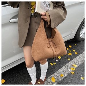 Detail view of brown faux suede tote bag featuring drawstring bow and metallic buckle