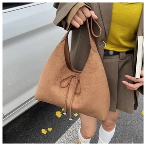 Detailed view of brown suede tote bag with drawstring bow and metal sphere charms