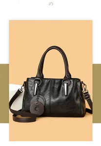 Detailed macro view of the black wrinkled leather texture and retro hardware on the tote bag