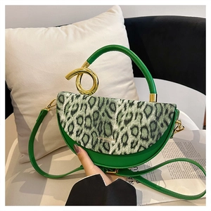 Macro detail of leopard print flap and golden metallic ring handle on green saddle bag