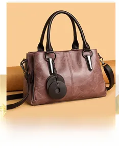 Close-up of vintage pink pebbled leather tote with dark brown handles and metal ring detail