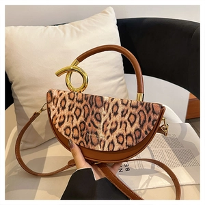 Detail of leopard print saddle bag featuring a unique twisted golden metal handle