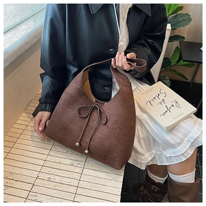 Detail of dark brown suede hobo bag featuring bow knot and silver metallic pendants