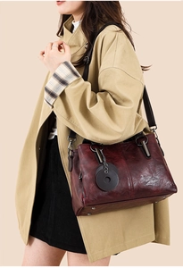Detail of burgundy glossy oil wax leather tote with wide strap and metallic rivets