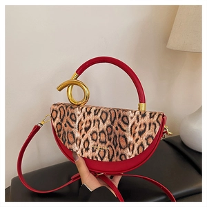 Detailed view of red leather leopard print handbag with golden metal ring and handle