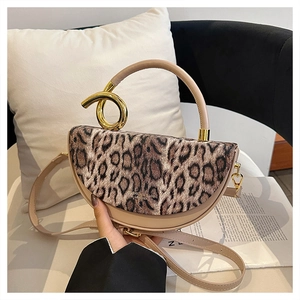 Detail of leopard print handbag with a unique twisted gold metal handle and beige leather