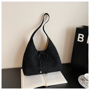 Detailed view of the black suede tote bag with delicate drawstring and metal ball charms