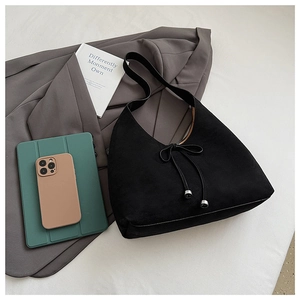 Close-up of black suede hobo bag featuring a bow detail and metallic drawstring accents