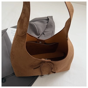 Detail of brown suede tote bag featuring inner pocket and delicate tie closure design