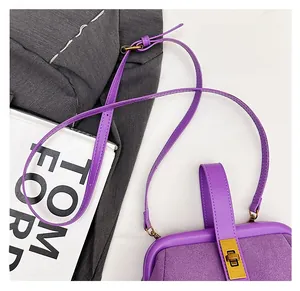 Detail of purple suede shell bag with golden twist lock and textured leather shoulder strap