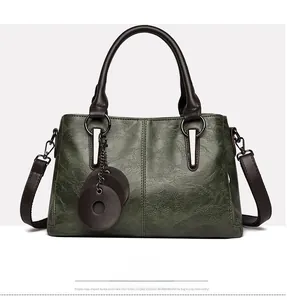 Close-up of dark green tote bag with brown handles and decorative circular leather tags