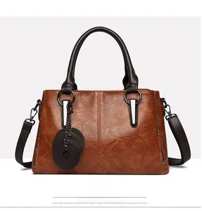 Front view of brown leather tote bag with contrast stitching and decorative charms
