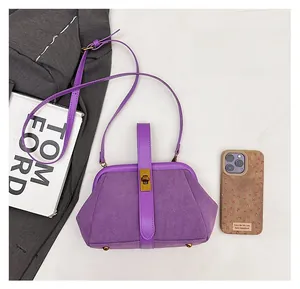 Detail of purple matte suede shell bag with golden metal clasp and leather strap