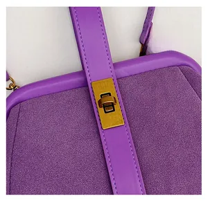 Macro detail of purple suede shell bag featuring vintage bronze twist lock and stitching