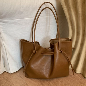 Dark brown minimalist leather tote bag with stylish drawstring details and long shoulder straps