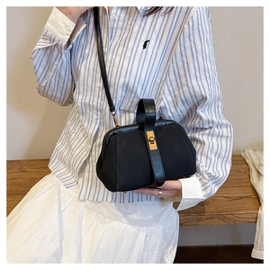Chic black matte shell bag featuring vintage gold clasp and cross-body strap shown on model