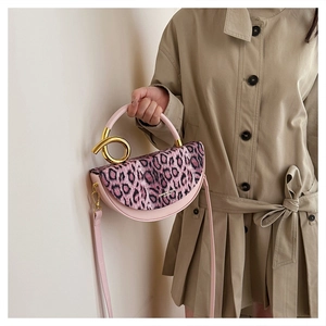 Detailed view of the leopard print flap and golden metal circular handle on a pink bag