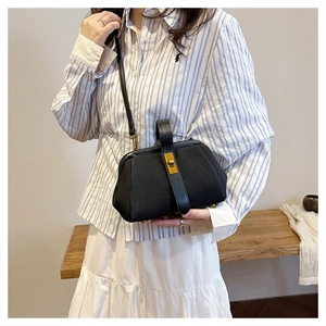 Detail of vintage black shell bag with elegant gold clasp and textured matte finish