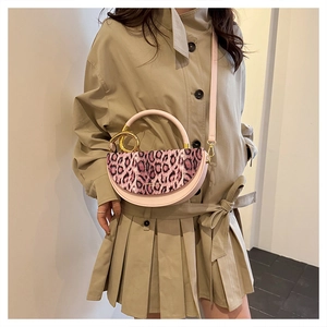 Detail of pink leopard print flap and gold ring handle on a compact crossbody bag