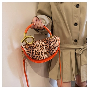 Detail of orange half-moon bag with leopard print flap and golden metal handle