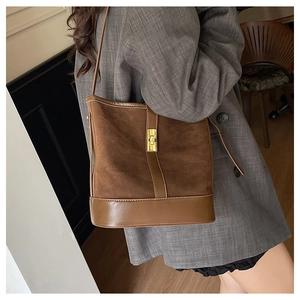 Close-up of retro brown bucket bag with matte texture and gold metal twist lock buckle