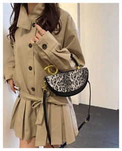 Detail of leopard print handbag with golden ring handle shown by a model