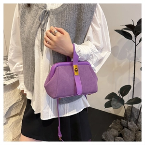 Detail of purple frosted leather shell bag with golden metal clasp and crossbody strap
