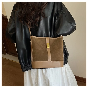 Detailed view of vintage dark brown suede bucket bag worn by model in black leather jacket