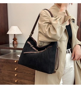 Détail d'un grand cabas noir mat avec des lanières en cuir marron et boucles dorées
