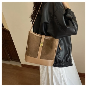 Detailed side view of vintage caramel brown bucket bag with metal turn-lock on a model