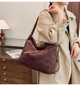 Détail d'un sac bandoulière en daim bordeaux avec sangle en cuir et boucles vintage