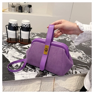 Detail view of purple matte shell bag with golden twist lock on marble surface