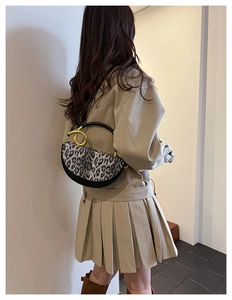 Detail view of leopard print crossbody bag featuring iconic gold ring handle on a model