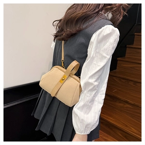 Detail of beige frosted shell bag with glossy leather trim and gold twist lock closure