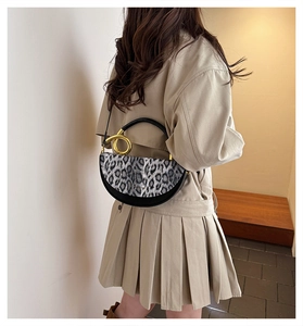 Detail of trendy leopard print handbag featuring a bold gold ring handle and leather texture