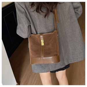 Close-up of vintage brown suede and leather bucket bag with golden metal twist lock