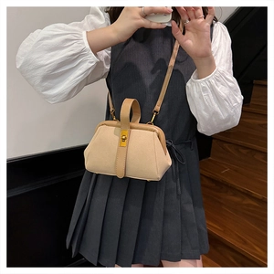Detail of khaki suede crossbody shell bag with gold rotary lock worn by model