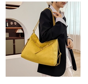 Gros plan du sac porté épaule en daim jaune avec sangles croisées et boucles en métal