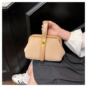 Detail of two-tone shell handbag with golden twist-lock and matte suede texture