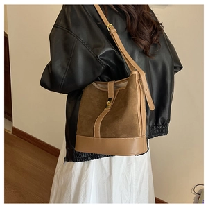 Close-up of vintage suede bucket bag with leather trim and gold metal buckle detail
