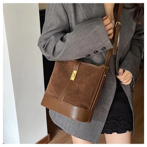 Detail view of brown suede bucket bag with gold square buckle and leather trim