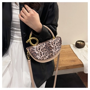 Detailed close-up of leopard print handbag with golden twisted metal handle and fine strap