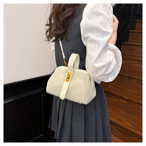 Chic beige matte shell bag shown on model featuring elegant gold metal clasp and strap