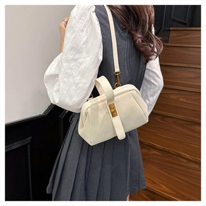 Close-up of cream shell handbag with golden twist lock worn by a model on stairs