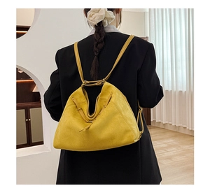 Détail du sac trapèze en daim jaune montrant les sangles latérales et la texture fine