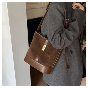 Close-up of vintage brown bucket bag with gold twist lock on grey blazer outfit