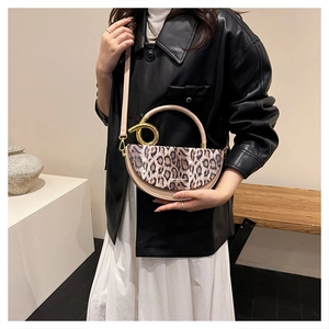 Close-up of leopard print handbag featuring a large gold circular metal handle and saddle shape