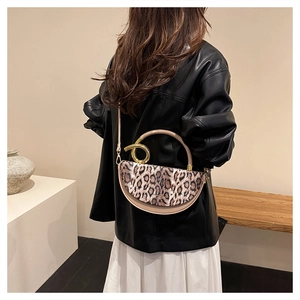 Detail of leopard print handbag with contrast handle and twisted gold hardware buckle