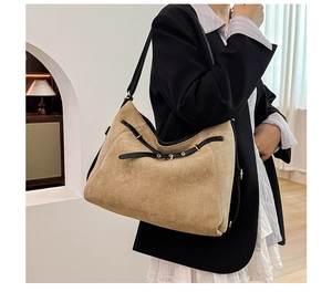 Détail du sac bandoulière en daim marron clair avec garniture en cuir et boucle dorée